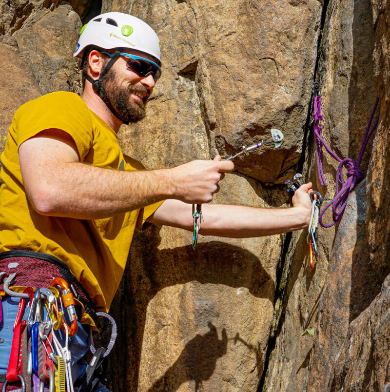 Trad climber in the learn to lead Trad climbing course practicing cam placement in a crack in order to build an anchor.