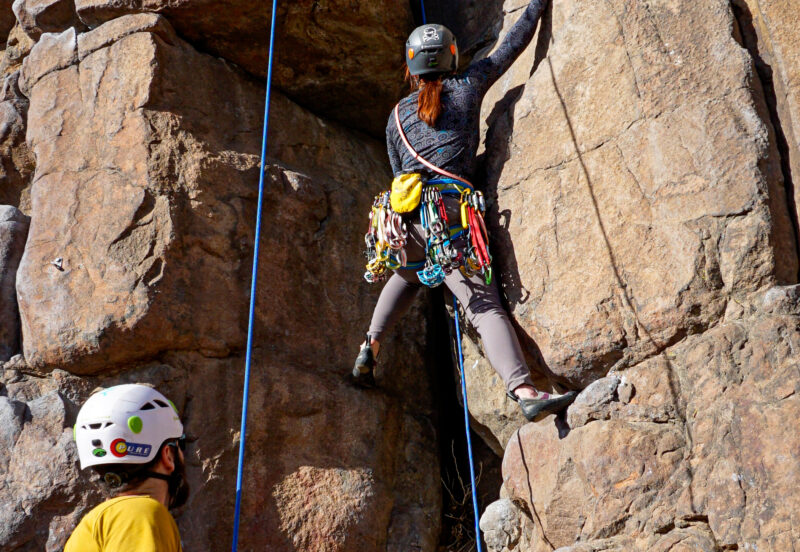 Beginner trad climber undertaking a mock lead climb with a safety top rope during our Learn to Lead Trad climbing course.